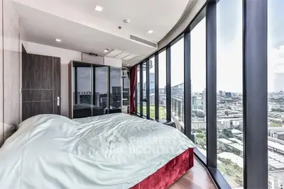 Luxurious bedroom with panoramic city view and floor-to-ceiling windows in modern high-rise apartment.