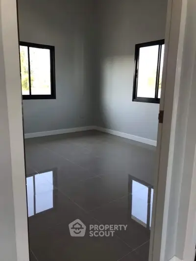 Spacious empty room with glossy tiled floor and large windows, perfect for customization.