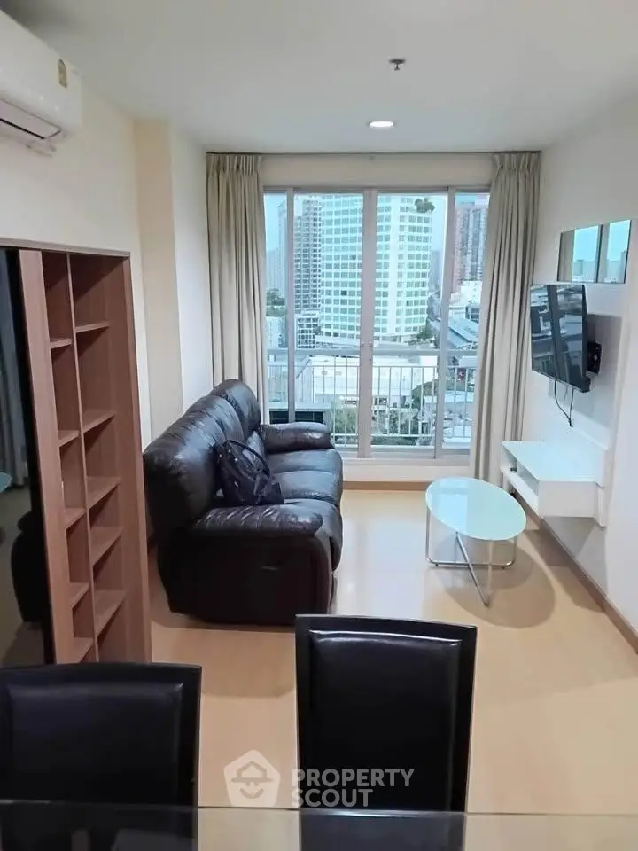 Modern living room with city view, featuring sleek furniture and large windows for natural light.