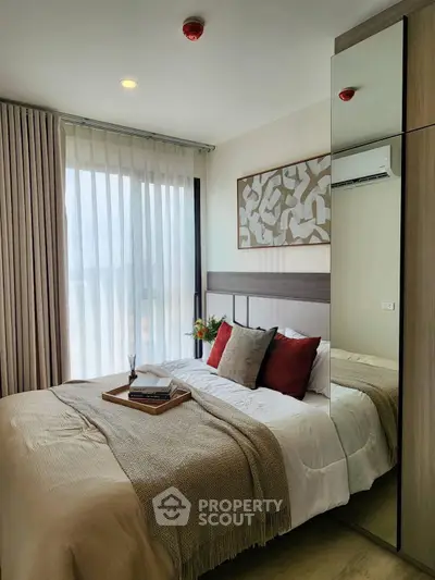 Cozy bedroom with modern decor, large window, and stylish bedding in a contemporary apartment.