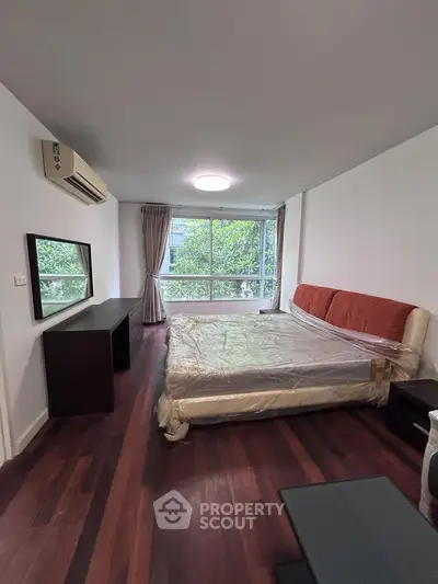 Spacious bedroom with large window and modern furnishings in a serene setting.