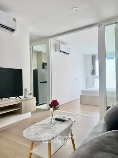 Modern living room with open layout, featuring sleek furniture and a view into a cozy bedroom.