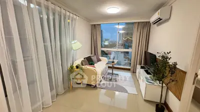 Cozy living room with modern decor and city view, featuring a comfortable sofa and entertainment unit.