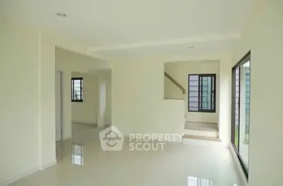 Spacious modern living room with large windows and sleek staircase