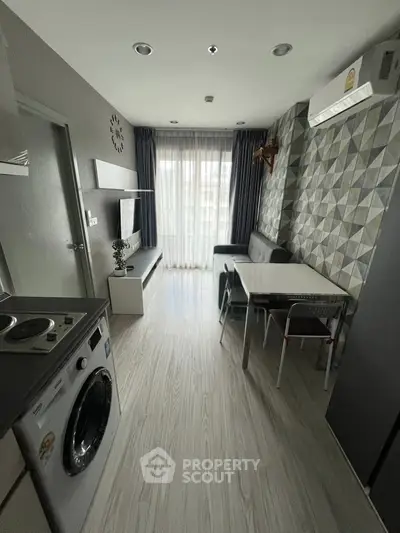 Modern living room with stylish decor and natural light, featuring a washing machine and dining area.