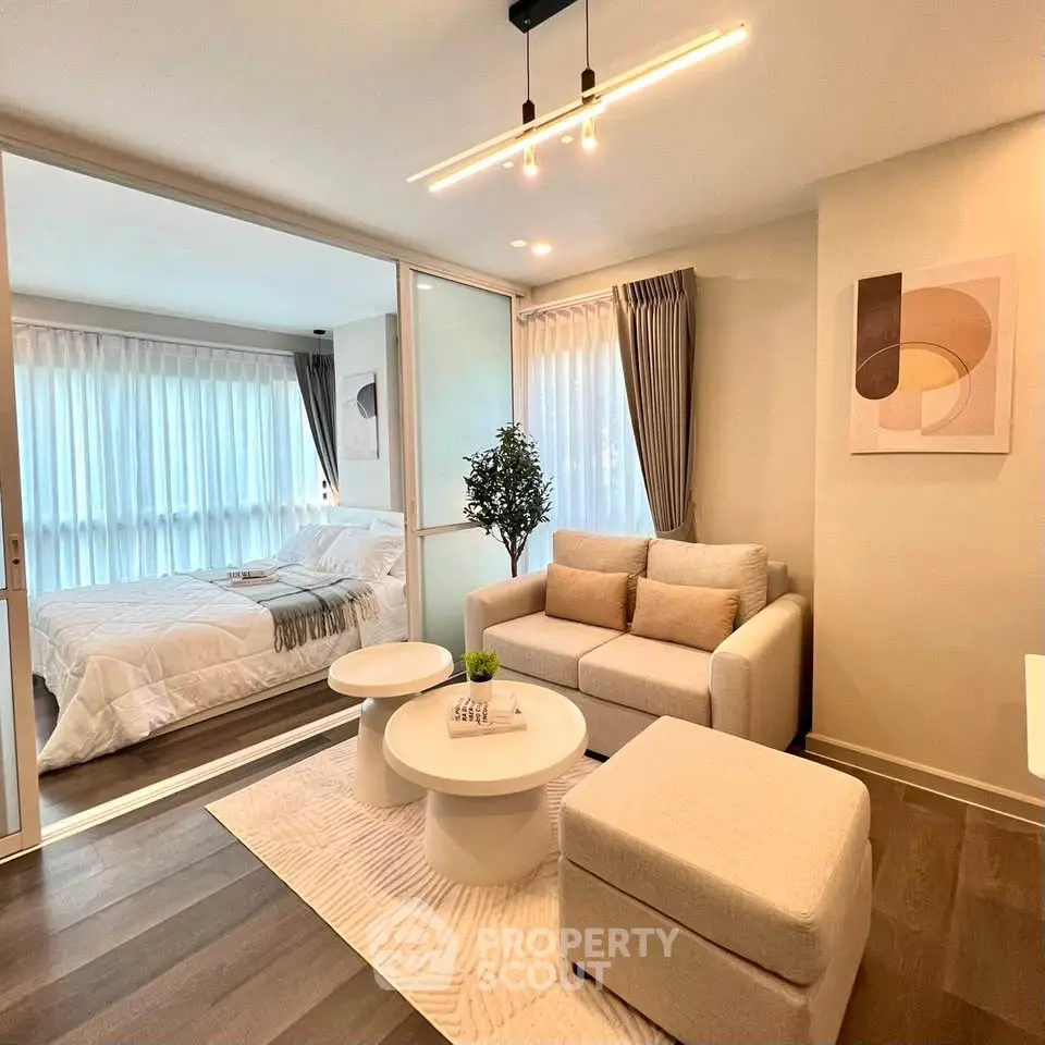 Modern living room with cozy seating and elegant bedroom view through glass partition.