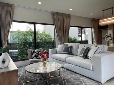 Stylish living room with modern decor and large windows overlooking greenery.