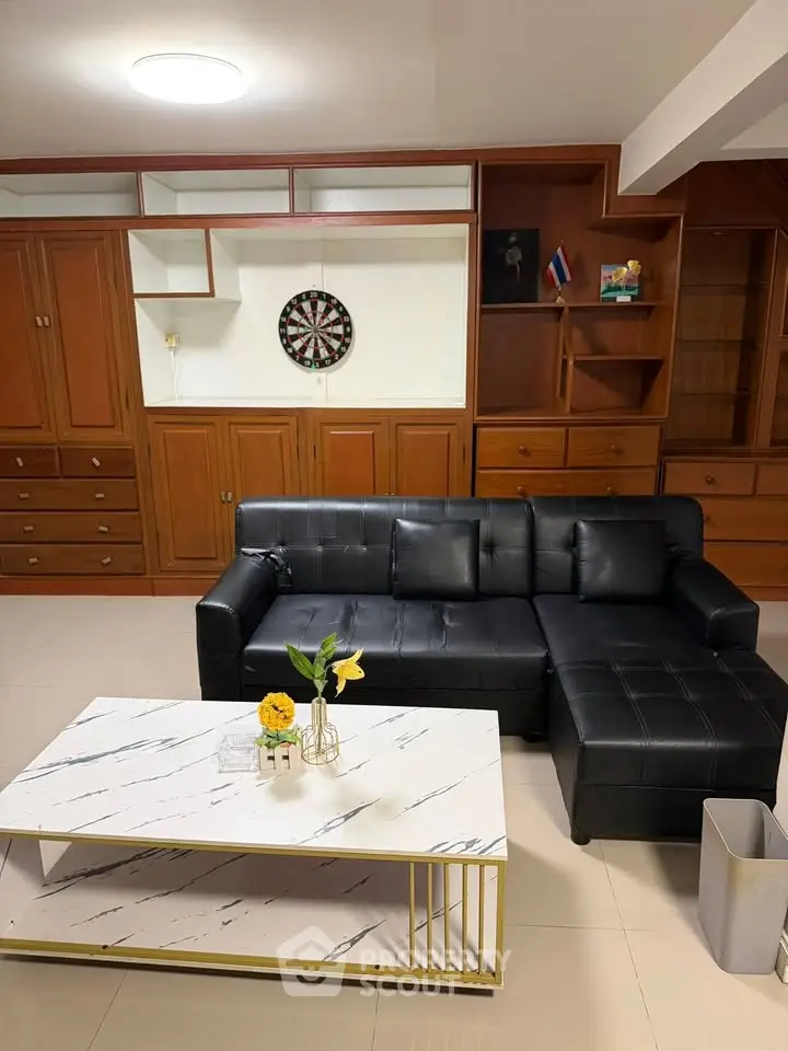 Stylish living room with black leather sofa and modern marble coffee table, perfect for relaxation.