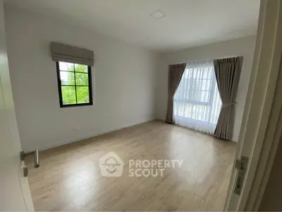 Spacious empty bedroom with large windows and wooden flooring