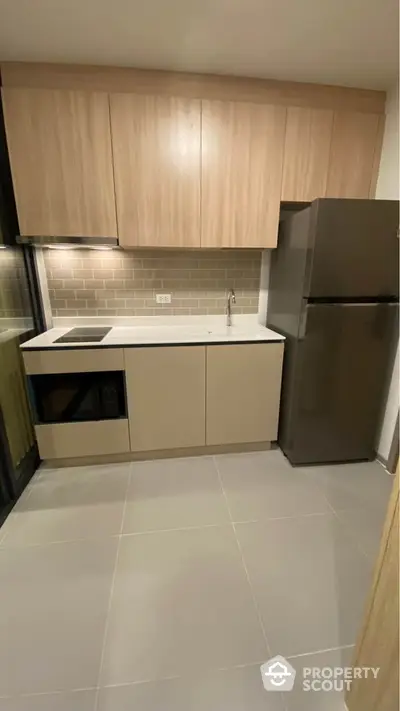 Modern kitchen with sleek cabinetry and stainless steel fridge in contemporary apartment.