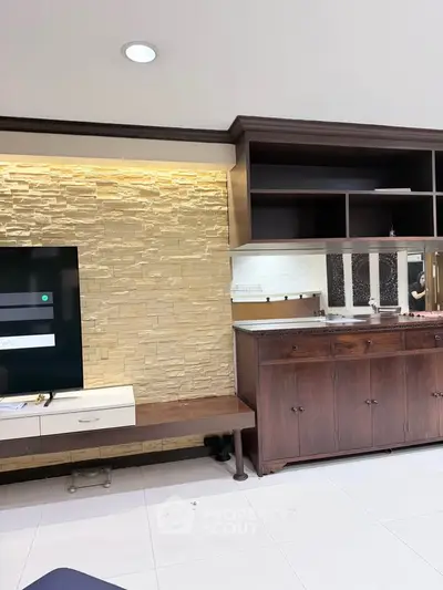 Spacious living room with modern stone accent wall and elegant wooden cabinetry.