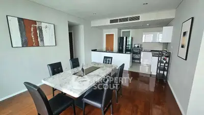 Modern open-layout kitchen and dining area with sleek furnishings and contemporary art.