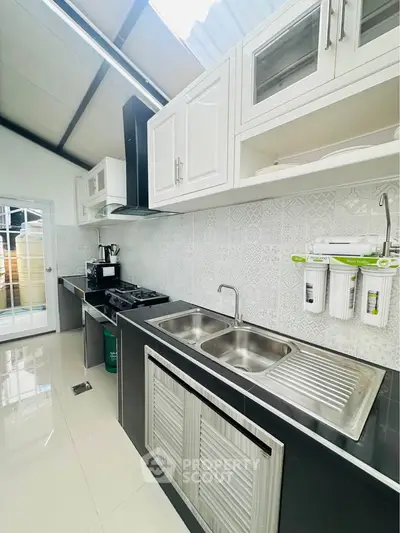 Modern kitchen with sleek cabinetry, dual sinks, and gas stove in a bright, airy space.