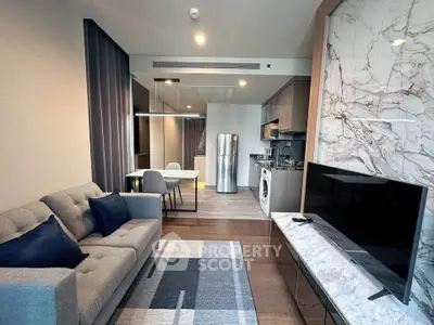 Modern living room with open kitchen, featuring sleek appliances and stylish decor.