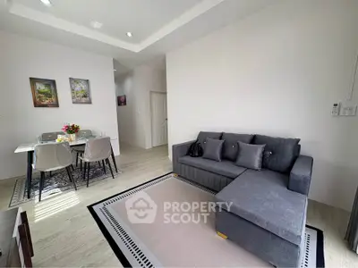 Modern living room with stylish gray sofa and elegant dining area in a bright, open space.
