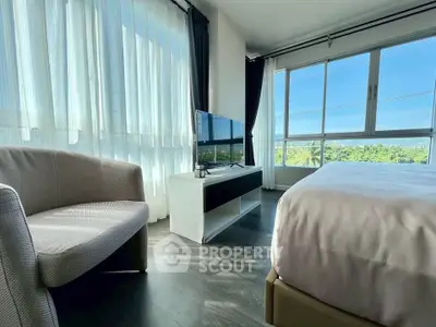 Bright bedroom with large windows and scenic view, featuring modern furniture and sleek flooring.