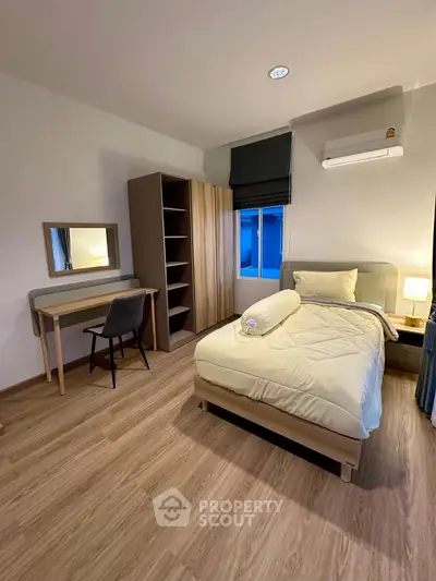 Cozy bedroom with modern furniture and wooden flooring, featuring a study desk and ample storage space.
