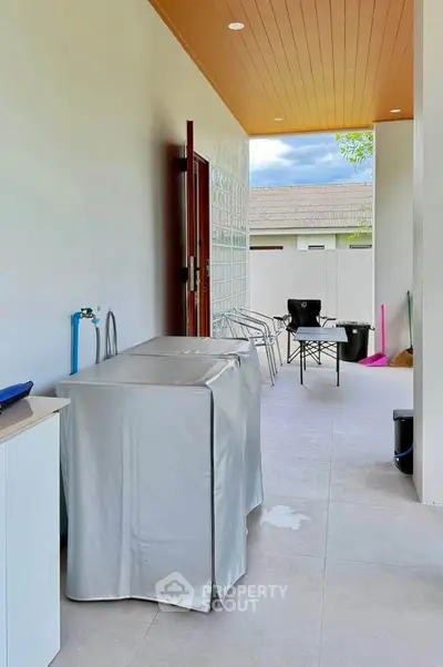 Spacious covered outdoor area with modern seating and storage, perfect for relaxation and entertainment.