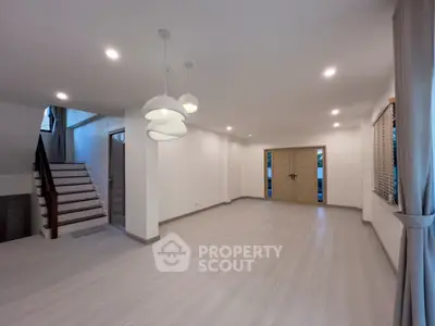 Spacious modern living room with elegant lighting and staircase in a stylish home.
