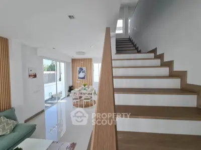 Modern open-plan living room with stylish staircase and dining area