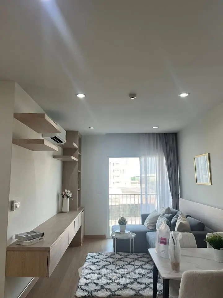 Modern living room with stylish decor and natural light, featuring a cozy sofa and elegant shelving.