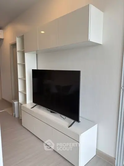 Modern living room with sleek white entertainment unit and flat-screen TV.