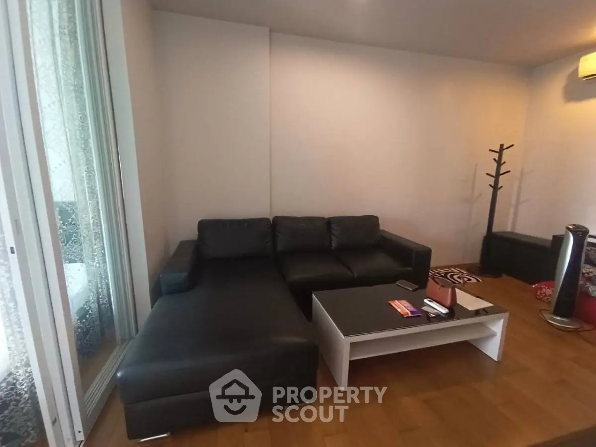 Modern living room with black leather sofa and sleek coffee table, perfect for relaxation.