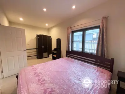 Cozy bedroom with large window and modern furnishings, perfect for relaxation and comfort.