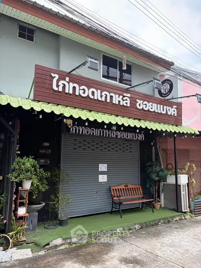 Charming commercial property with inviting storefront and seating area, perfect for a small business.