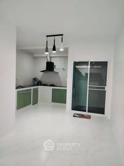 Modern kitchen with green cabinets and sleek lighting in a spacious open layout.