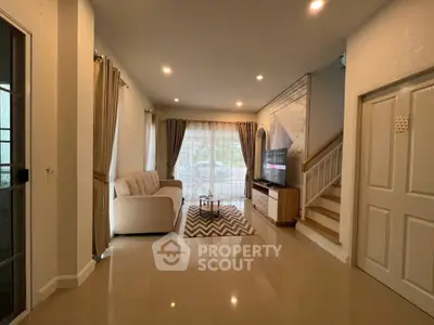 Spacious living room with modern decor and natural light, featuring a cozy sofa and stylish rug.