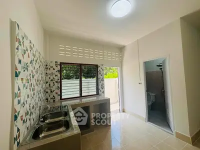 Spacious kitchen with dual sinks and modern tile backsplash, adjacent to a bathroom, offering functional design.