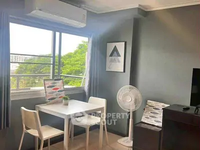 Cozy living room with modern decor and natural light, featuring a dining set and air conditioning.