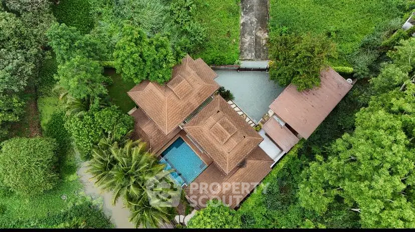 Stunning aerial view of a luxurious villa with lush greenery and private pool.