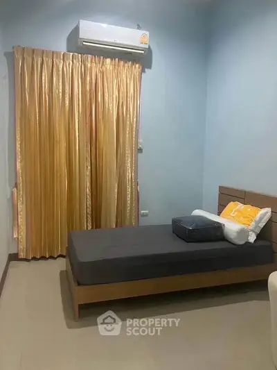 Cozy bedroom with elegant gold curtains and modern air conditioning unit.