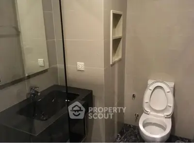 Modern bathroom with sleek black sink and white toilet in a minimalist design.