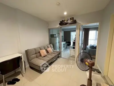Modern living room with cozy sofa and open layout leading to bedroom.