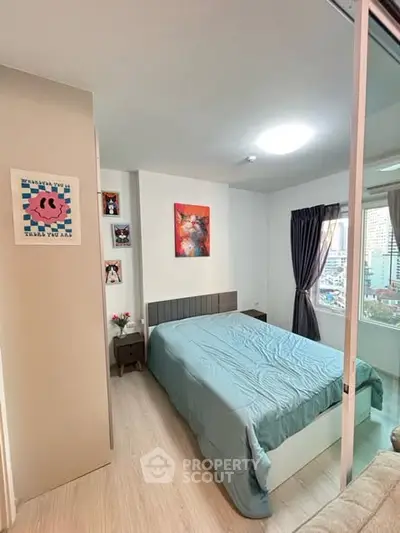 Cozy bedroom with modern decor and city view, featuring a comfortable bed and stylish artwork.