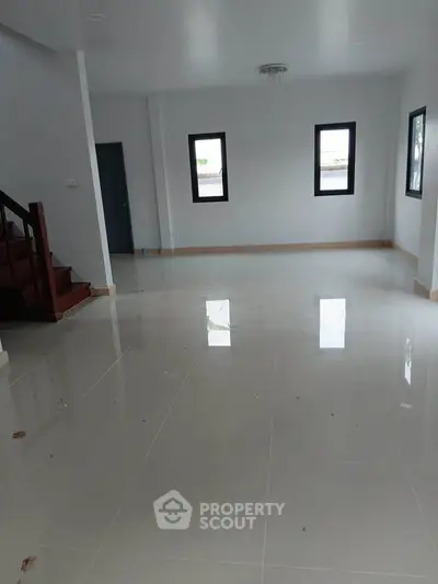 Spacious unfurnished living room with glossy tiled floors and large windows in a modern home.