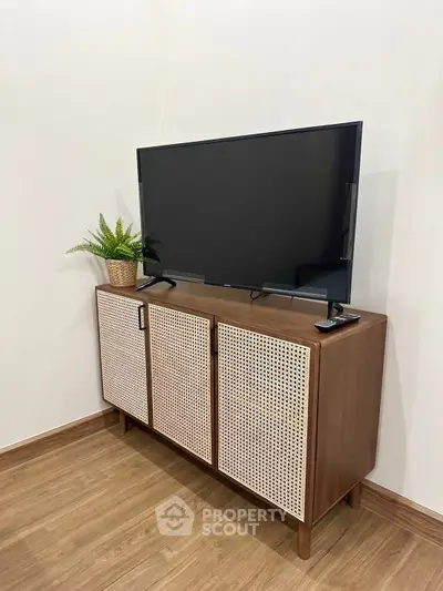 Stylish modern living room with wooden TV stand and flat-screen TV, perfect for cozy home entertainment.