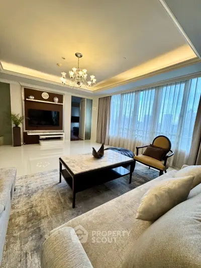 Luxurious living room with elegant chandelier and large windows offering stunning city views.