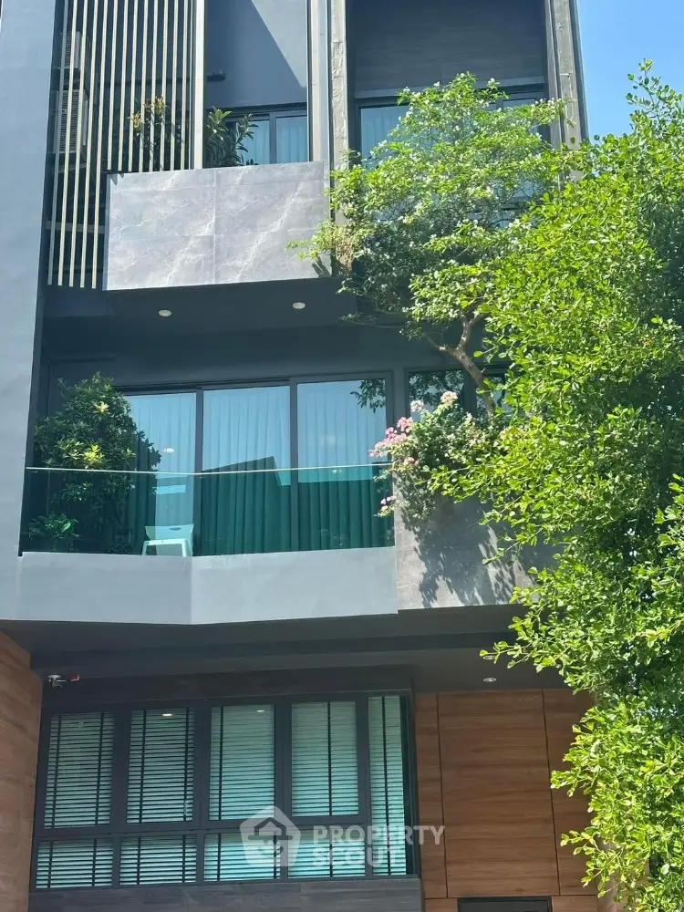 Modern multi-story building with lush greenery and glass balconies