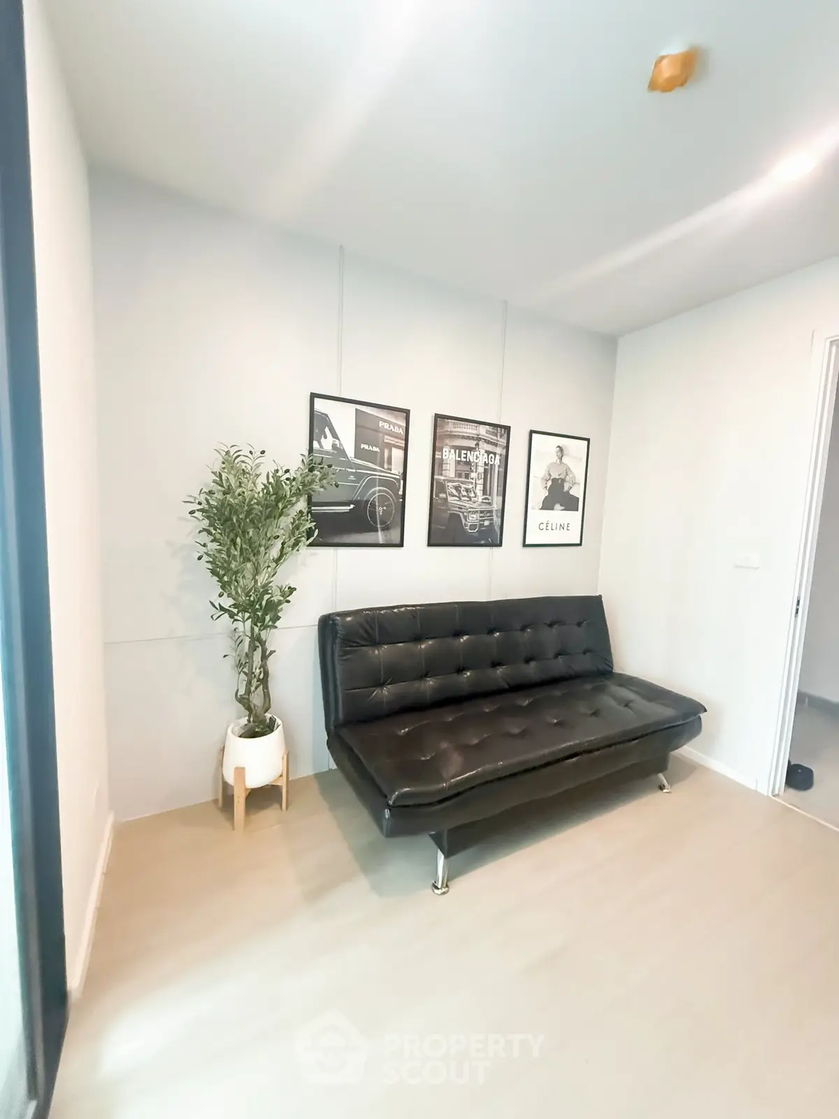 Stylish modern living room with black leather sofa and framed art on white walls.