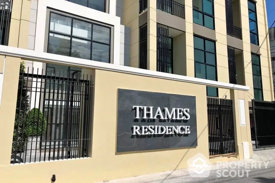 Modern facade of Thames Residence with sleek architectural design and gated entrance.