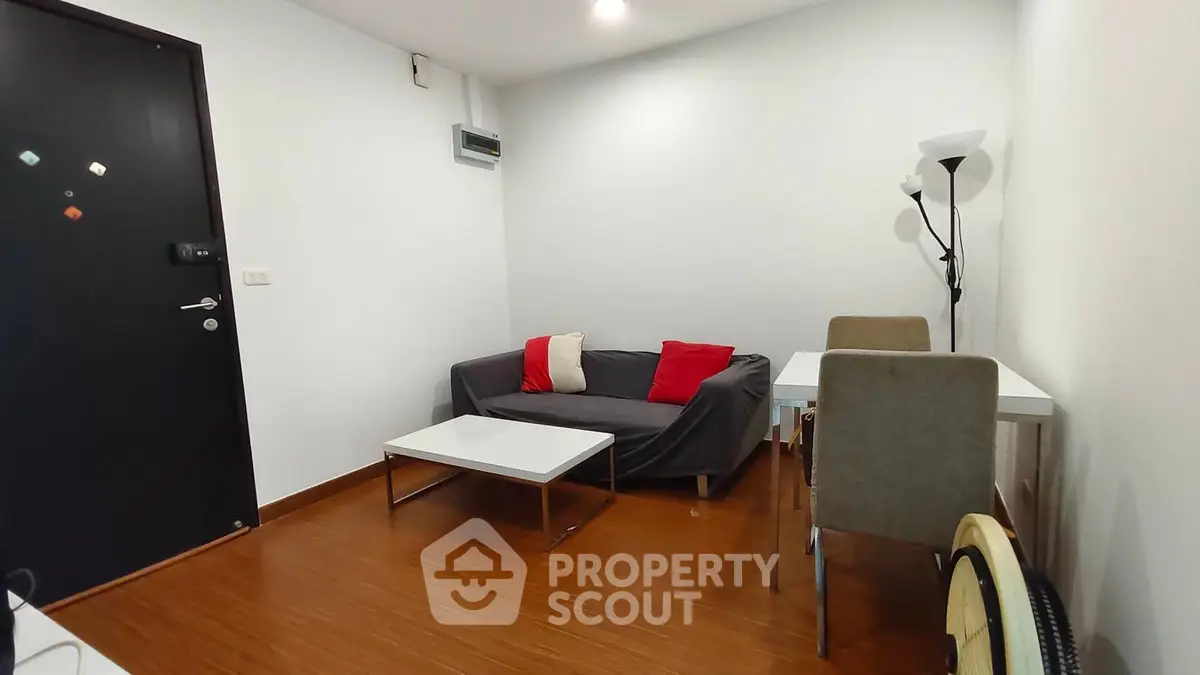 Cozy living room with modern furniture and wooden flooring in a compact apartment.