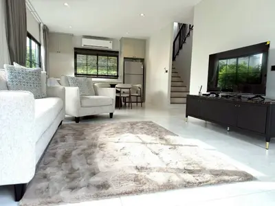 Spacious modern living room with plush rug and sleek furniture in a bright, airy home.