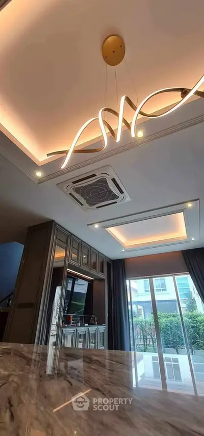 Luxurious modern living room with stylish lighting and large windows offering garden views.