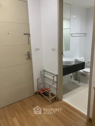 Modern bathroom entrance with wooden flooring and sleek fixtures