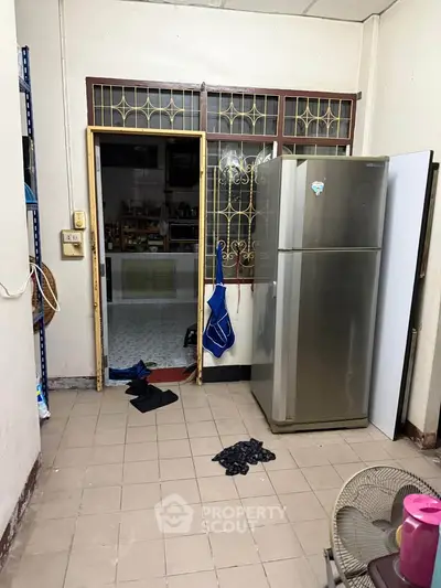 Cozy kitchen area with fridge and open door leading to pantry, ideal for compact living spaces.