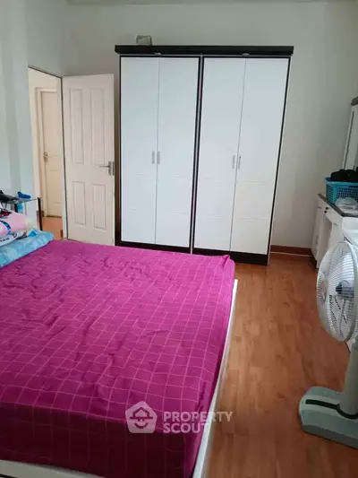 Spacious bedroom with wooden flooring and large wardrobe